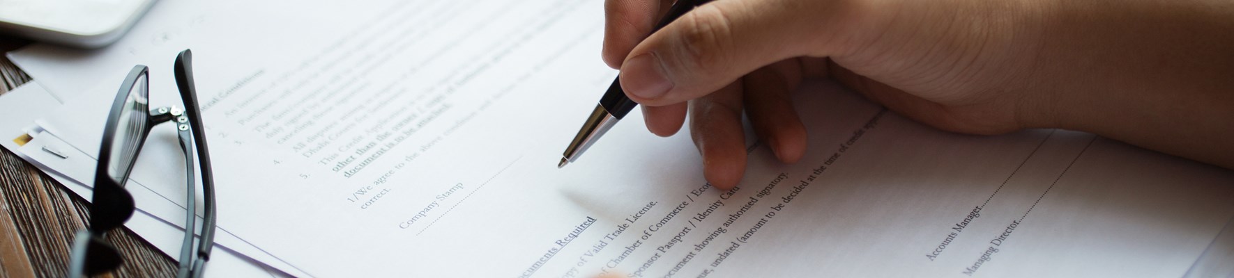 Person signing a document with a pen